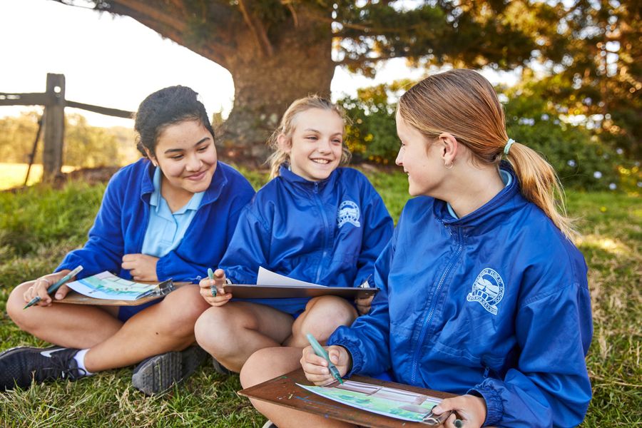 Students sitting on the hillside, creating a watercolour painting of the view towards the Blue Mountains.