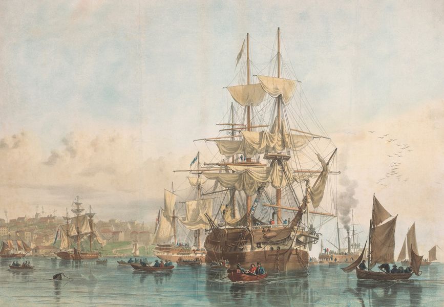 Several tall ships anchored in Sydney Cove with long boats unloading passengers. The headland that is the rocks can be seen in the background to the left of the frame.