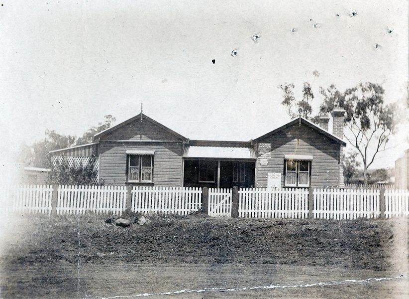 Building behind picket fence with gate shut.
